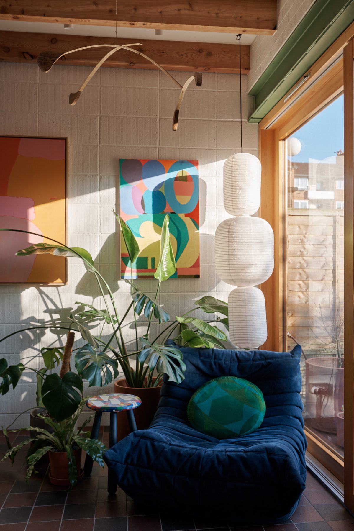 Sun room with a blue Togo sofa, paper lanterns and colourful art