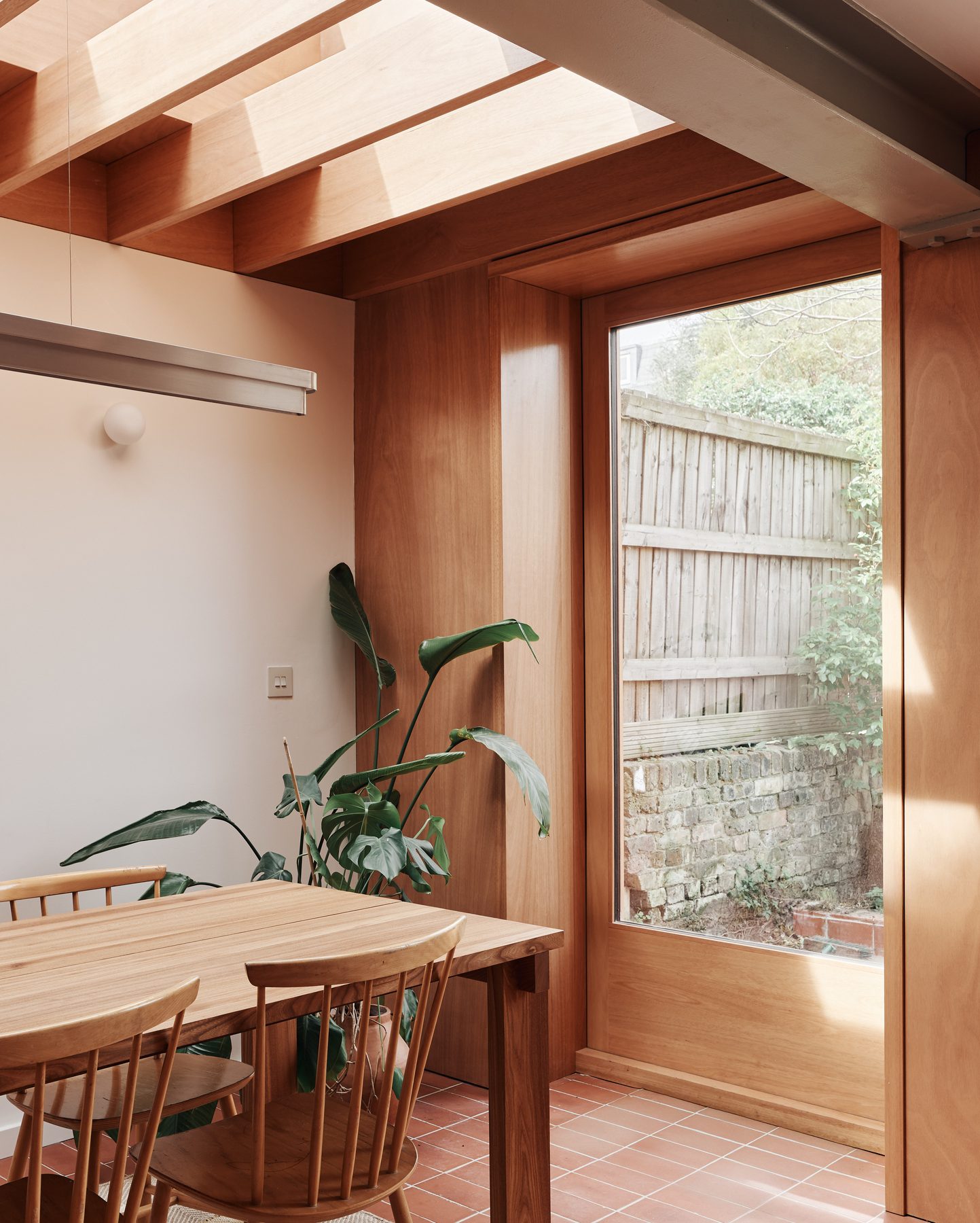 Timber-lined dining room opening to a garden