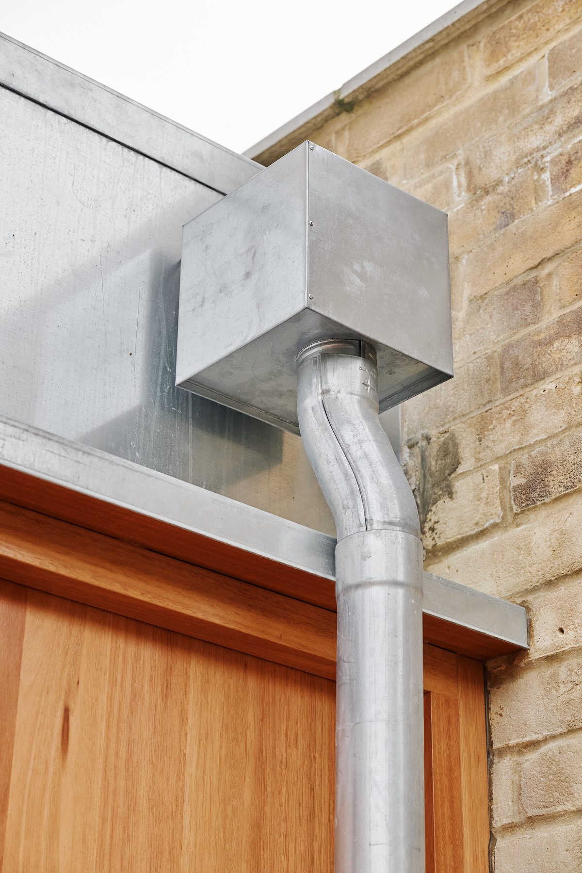Galvanised rainwater hopper against stock brick